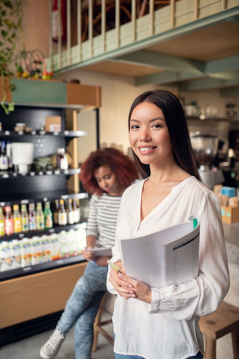 woman holding open sign and smiling because she has a business checking account with ascent bank